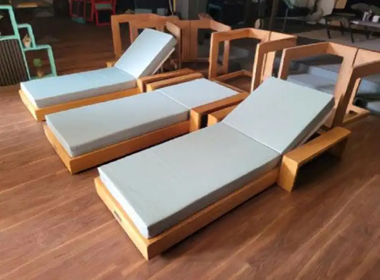 Premium pool lounges with comfortable cushions and timber frames beside a swimming pool and outdoor entertainment area.